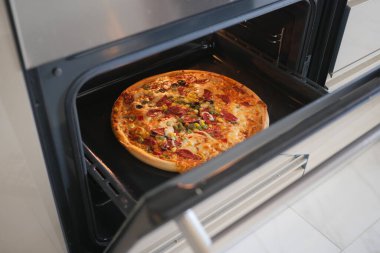 Lezzetli bir pizza fırında pişiyor, içinde malzemeler var..