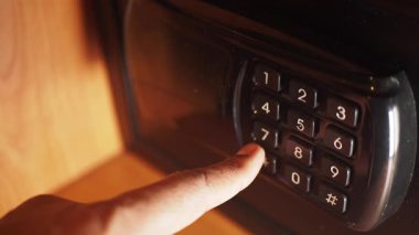 Bir kişi, bir kasayı açmak için şifreyi tuş takımına giriyor..