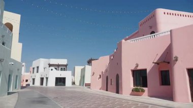 Parlak renkli binalar, güneşli bir kasabada yol boyunca uzanır..