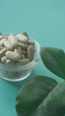 Yeşilliklerle çevrili cam bir kasede bitkisel takviyeler..