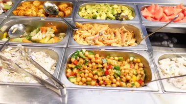 Öğle yemeğinde salata ve makarna dahil bir dizi renkli yemeğin tadını çıkarın..