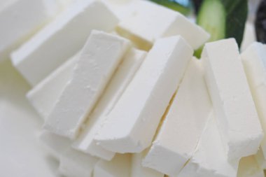 Yumuşak beyaz peynir düzgünce düzenlenir, kremsi dokusu ve şekli sergilenir..