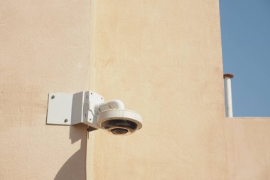 Yüksek çözünürlüklü bir güvenlik kamerası açık renkli bir duvara bağlı..
