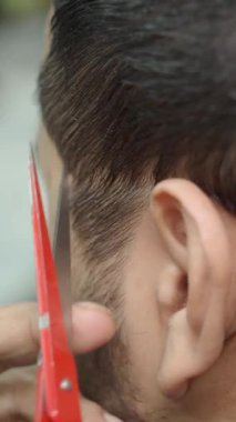 Bir berber, berber dükkanında saç kesimini ustalıkla yapar..