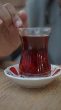 Bir insan kafede dinlenirken bir fincan aromatik çay karıştırır..