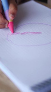 Bir çocuk kağıt üzerinde güzel sanat eserleri yaratmak için renkli boya kalemleri kullanır..