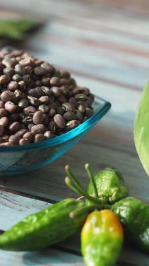 Fasulye, biber ve meyve ahşap bir yüzeye dizilmiştir..