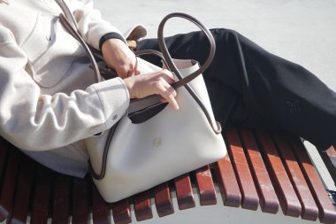 Tahta bir bankta otururken insan güneşli bir günün tadını çıkarır..