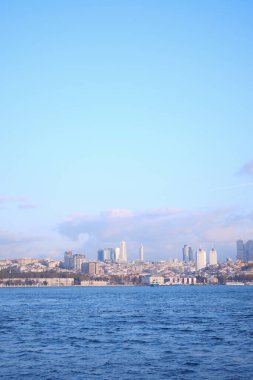 Modern yapılar, sakin mavi denizin yanında, rıhtımın üzerinde yükselir..