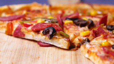 Çeşitli malzemeler ve aromalar içeren ağız sulandıran bir dilim pizzanın tadını çıkarın..