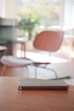 Bir akıllı telefon sıcak, davetkar bir iç mekânda bir masanın üzerine yerleştirilir..