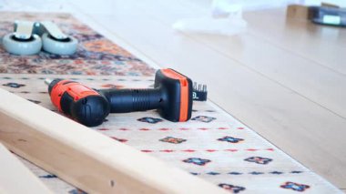 Aletler ve ahşap malzemeler kapalı alanda hafif bir halı üzerinde düzenlenir..