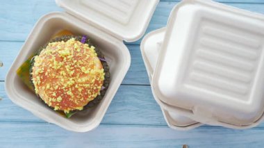 Bu lezzetli burger, tahtadan bir masanın üzerinde biyolojik olarak çözünebilir bir ambalajda duruyor..