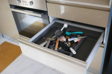 Çeşit çeşit mutfak aletleri modern bir mutfağın çekmecesinde dağınık olarak görülür..