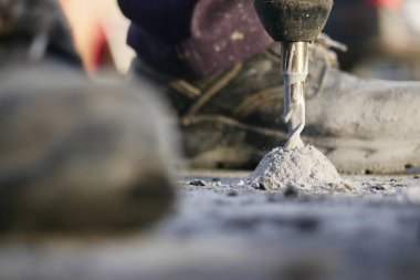 Bir inşaat işçisi beton yüzeyi matkapla delmiş..