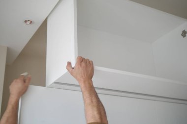 Bir kişi, çağdaş bir iç dekora beyaz bir raf yerleştiriyor..
