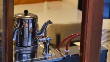 Tuhaf bir kafe atmosferindeki espresso makinesinin üzerinde dumanı tüten bir çaydanlık..