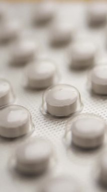 Düz bir yüzeyde su toplamış beyaz hapların yakın plan görüntüsü..