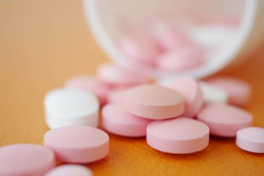 Pembe ve beyaz tabletler düz bir yüzeye dökülür..