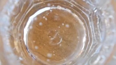 İçi köpüklü suyla dolu berrak bardakta kabarcıklar görünüyor.
