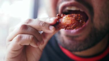 Sıradan bir restoranda leziz bir tavuk kanadının tadını çıkarıyor..