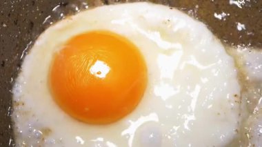 Taze bir yumurtanın cızırdayan tavada yavaşça pişişini izleyin..