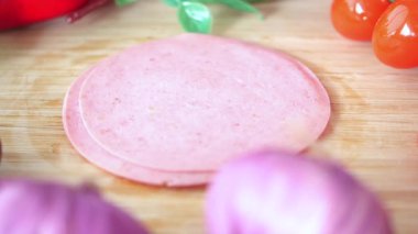 Yemek hazırlamak için canlı sebzelerle birlikte salam dilimliyorum..