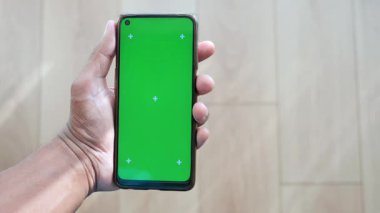 Birisi grafikler için canlı yeşil ekran içeren bir akıllı telefon görüntüler.