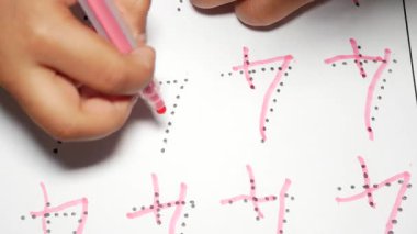 Çocuk renkli işaretler ve noktalar kullanarak numara yazma alıştırması yapıyor.