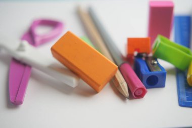 Sıradan bir şekilde düzenlenmiş kalem ve silgi gibi çeşitli kırtasiye ürünleri.