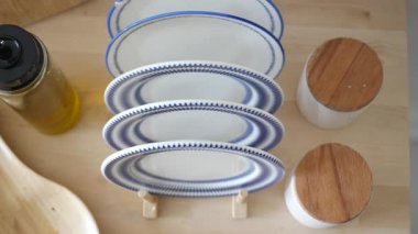 Masadaki ahşap kapların yanında güzel düzenlenmiş mavi ve beyaz tabaklar..