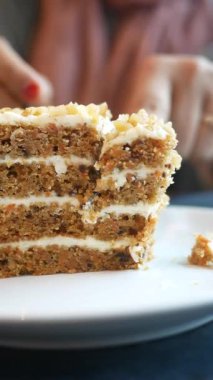 Bir el, arkadaş canlısı bir kafede bir dilim havuçlu kek kesiyor..