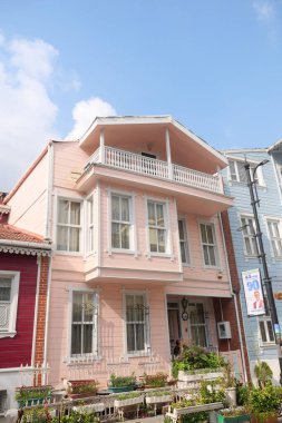 Mavi gökyüzünün altında, resim gibi bir alanda balkonu olan parlak pembe bir ev..