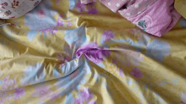 Çiçekli ve renkli yastıklı rahat bir yatak rahatlamaya davetiye çıkarır..