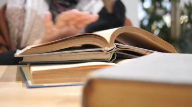 Bir insan sıcak bir ortamda birden fazla kitap okumaya dalmıştır..