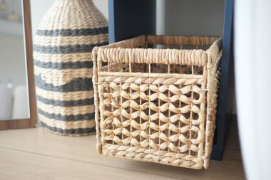 Konforlu bir odada, dekoratif bir vazonun yanında örülmüş bir sepet duruyor..