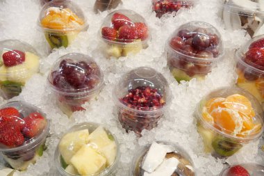Buzda satılık çeşitli meyvelerle dolu renkli meyve bardakları..