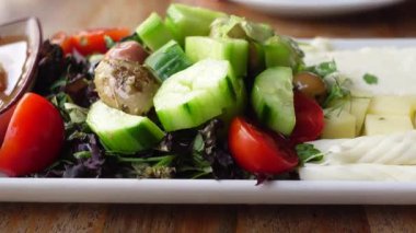 Öğle yemeğinde salatalıklı, domatesli ve zeytinli canlı bir salatanın tadını çıkarıyorum..