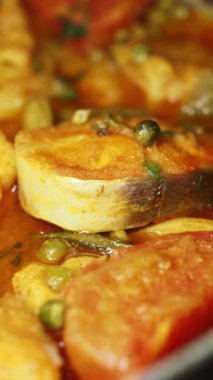 Balık güveci olgun domates ve lezzet için otlarla kaynıyor..