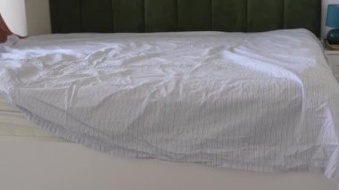 Parlak bir odada temiz çarşaf ve yatak düzenlemek..