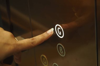 Bir el asansörün zemin katının düğmesine basıyor..