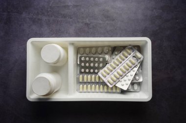 Çeşitli ilaç şişeleri ve paketleri gri bir yüzeye yerleştirilmiştir..