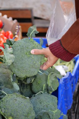 Sonbaharda kalabalık bir markette taze brokoliyi denetleyen biri..