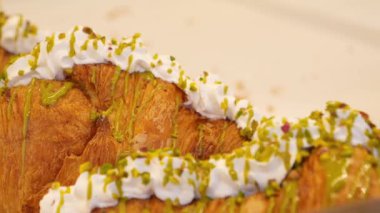 Şekerli krema ve ezilmiş fıstıkla süslenmiş çöreklerin tadını çıkar..