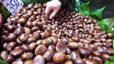 Müşteriler sonbahar kestaneleriyle dolu canlı bir pazarı keşfediyorlar..
