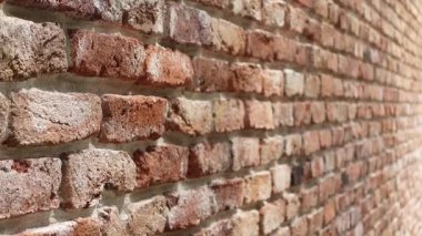 Bir tuğla duvarın dokularını ve renklerini vurgulayan yakın plan bir görünüm.