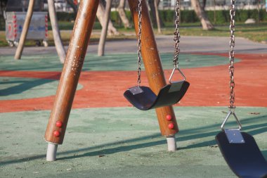 Boş salıncaklar yavaşça sallanıyor Parktaki sıcak öğleden sonra güneşinin altında.