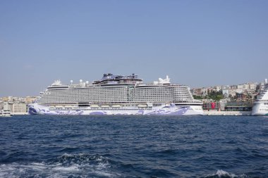 Büyük yolcu gemisi kıyıda dinleniyor, şehir manzarası sergiliyor..