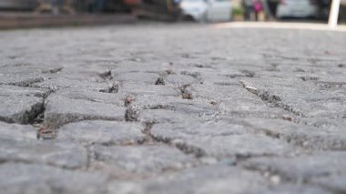 Görünür çatlaklar ve çimen büyüyen bir kaldırım taşı sokağının yakın çekimi..