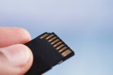 Bir kişi, metalik bağlantılarını gösteren mikro bir SD kart tutuyor..